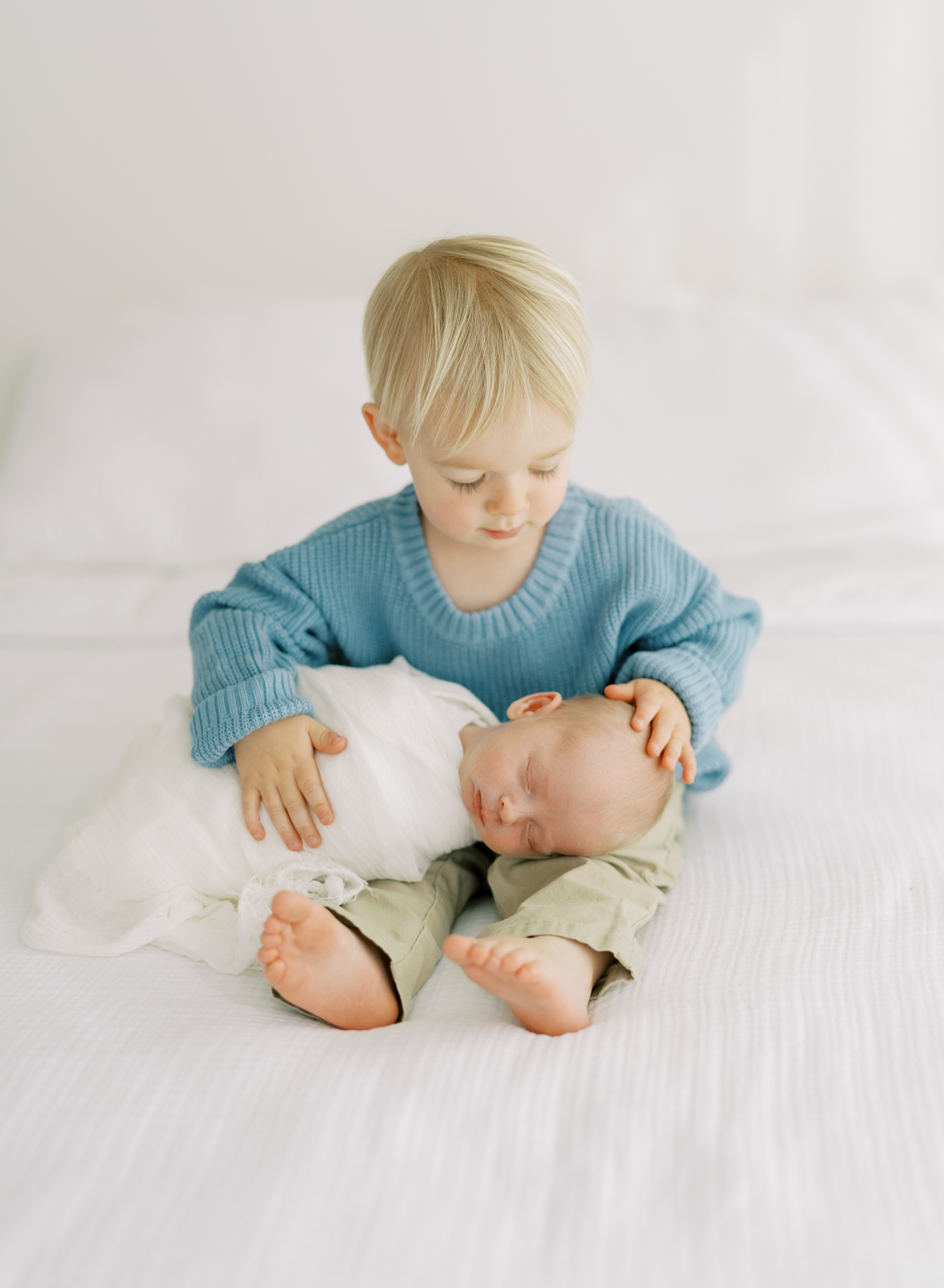 toddler brother looking at newborn brother during studio newborn photoshoot