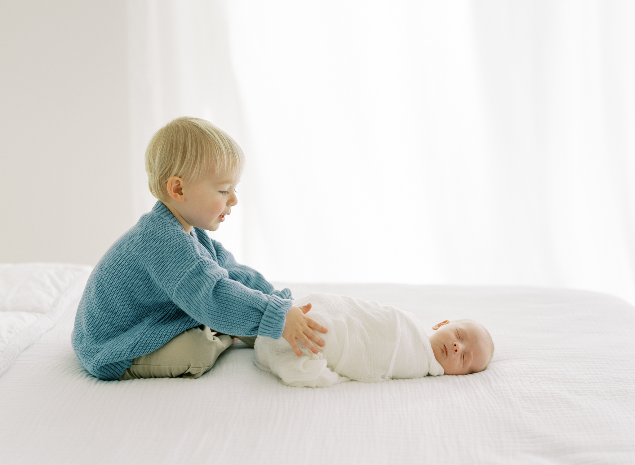 toddler brother looking at newborn brother during studio newborn photoshoot