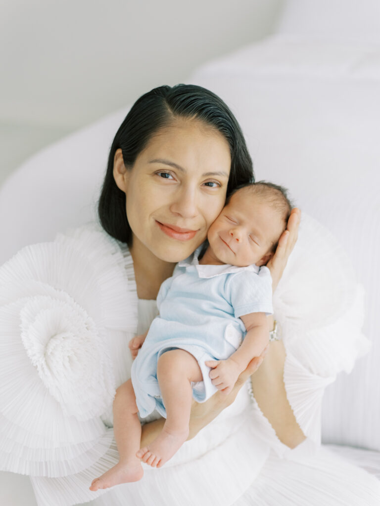 Stunning mama holding smiling newborn son up to her cheek during newborn photoshoot in Cumming, GA.