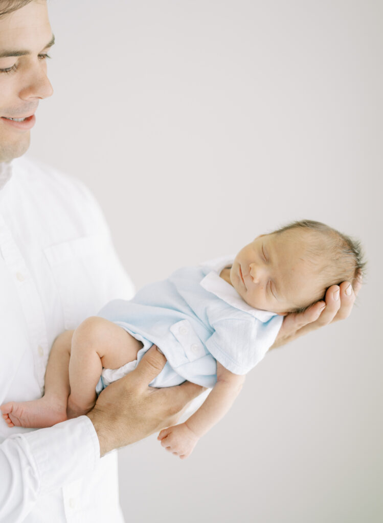 Dad holding tiny baby in the palm of his hands. 