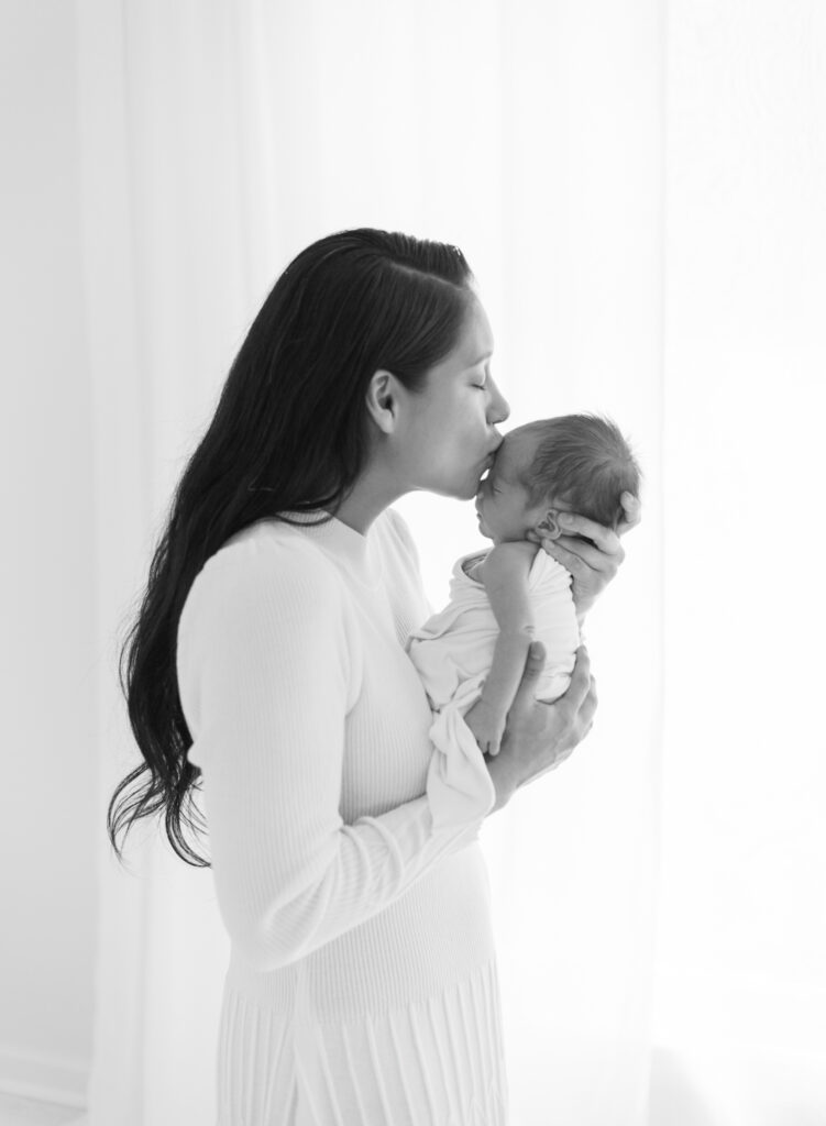 Black and white and backlit image of mom kidding newborn son in Cumming, GA photography studio. 