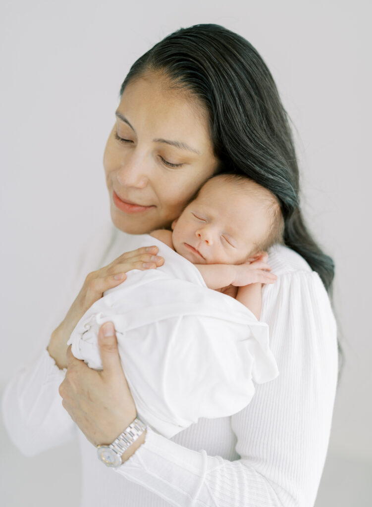 Newborn baby resting on mom's shoulder for clean, natural newborn photos in Cumming, GA.